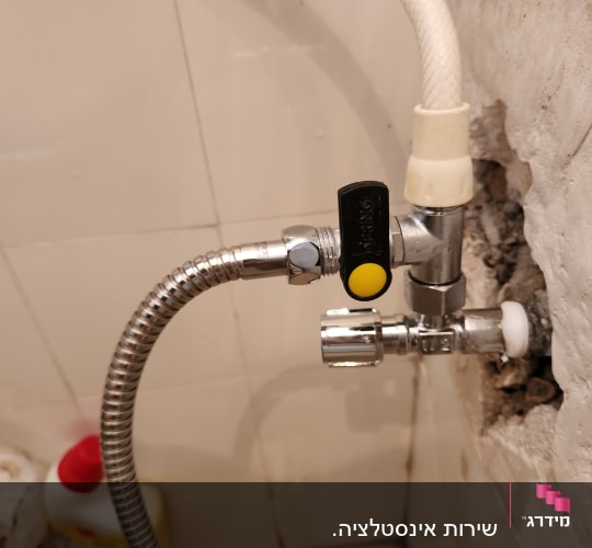 צינור מים מחובר לשסתום מתכת בקיר